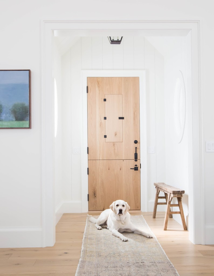 blonde wood Dutch door with bench in foyer by Amber Interiors