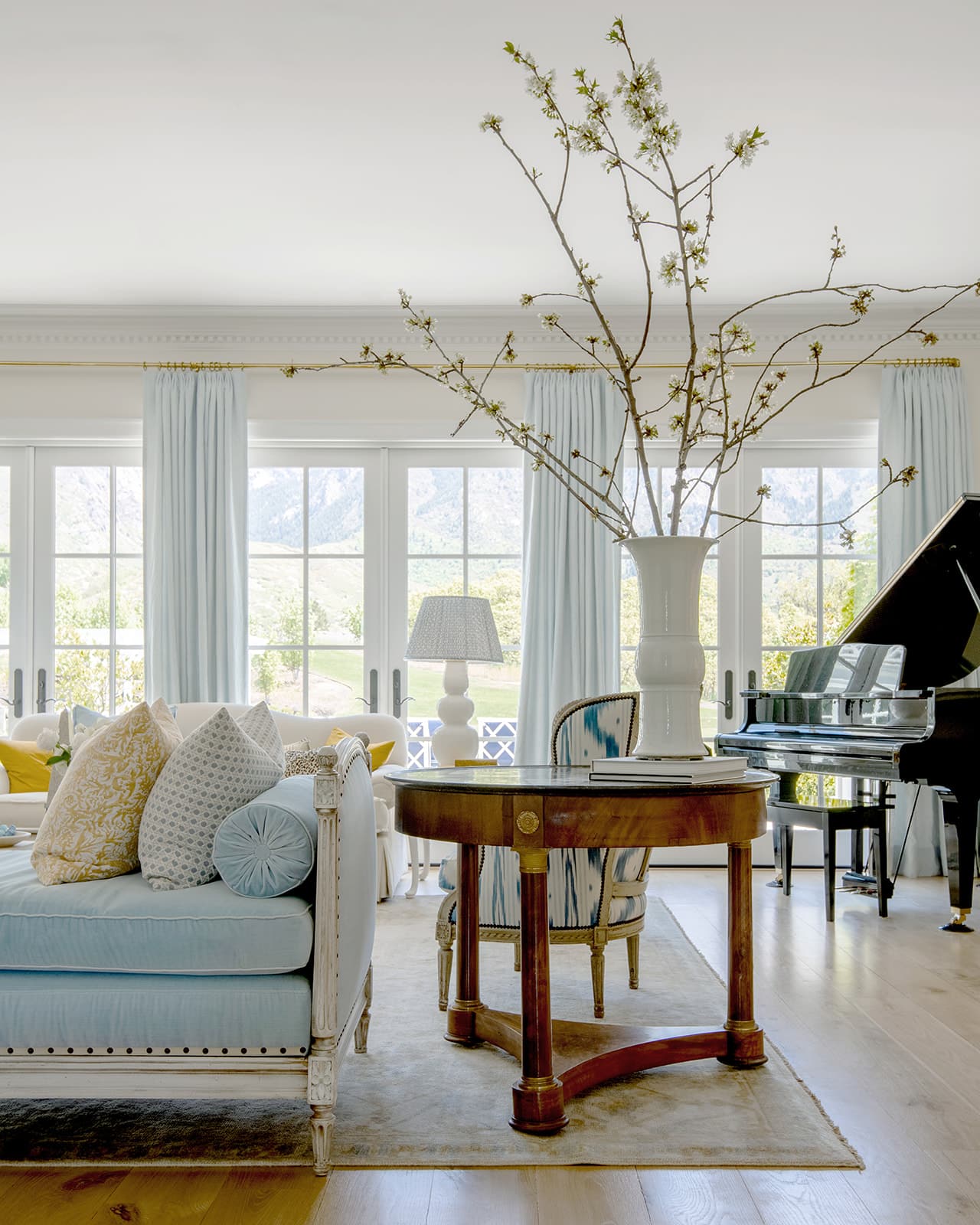 Heather Nan PhotographyHilary Taylor's  work exudes a sense of refined sophistication, creating spaces that are both timeless and inviting. Using beautiful interior design ideas, Taylor combines colors, textures, and patterns to achieve a sense of balance. Blue and white living room with large branches in vase on a round table